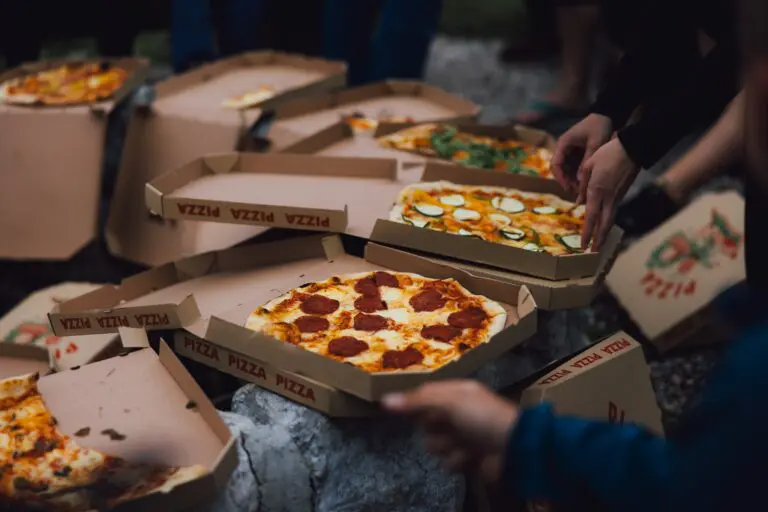 people sharing pizzas from cardboard boxes outdoors