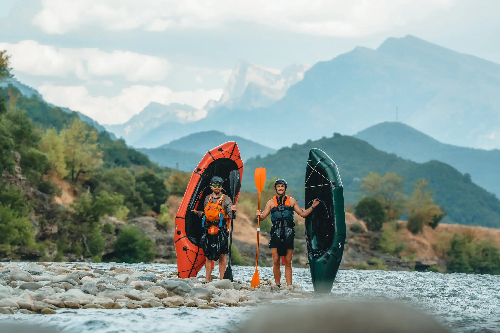 deux hommes avec des packrafts et des pagaies sur une berge rocheuse