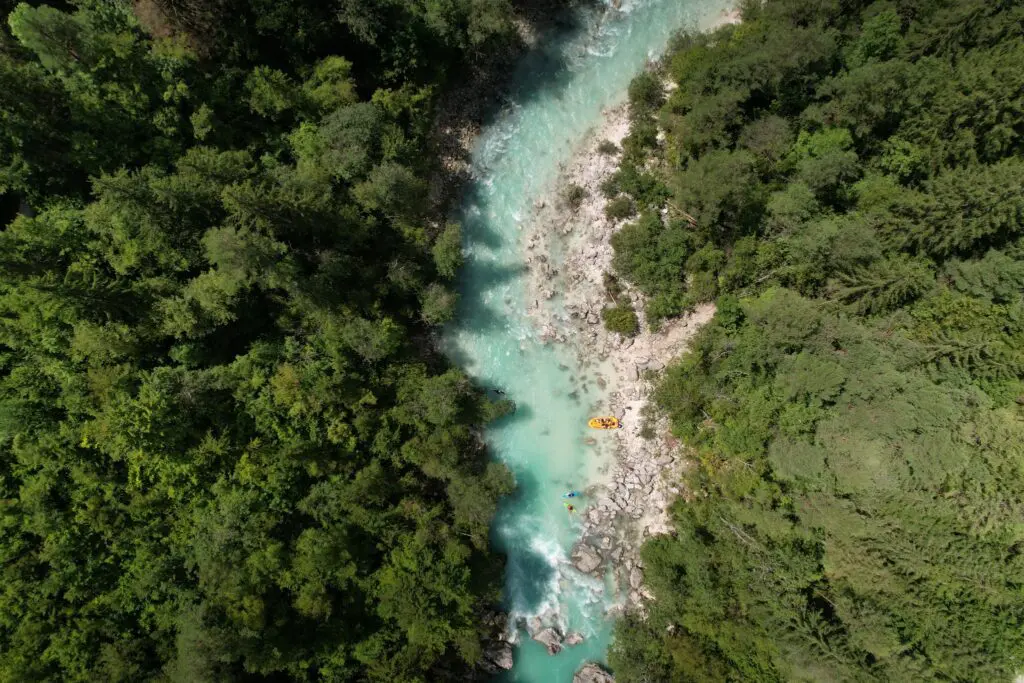 drone shot of turquoise river with packrafters in Slovenia