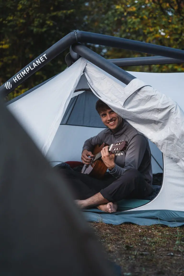 man playing guitar inside tent, camping in Slovenia