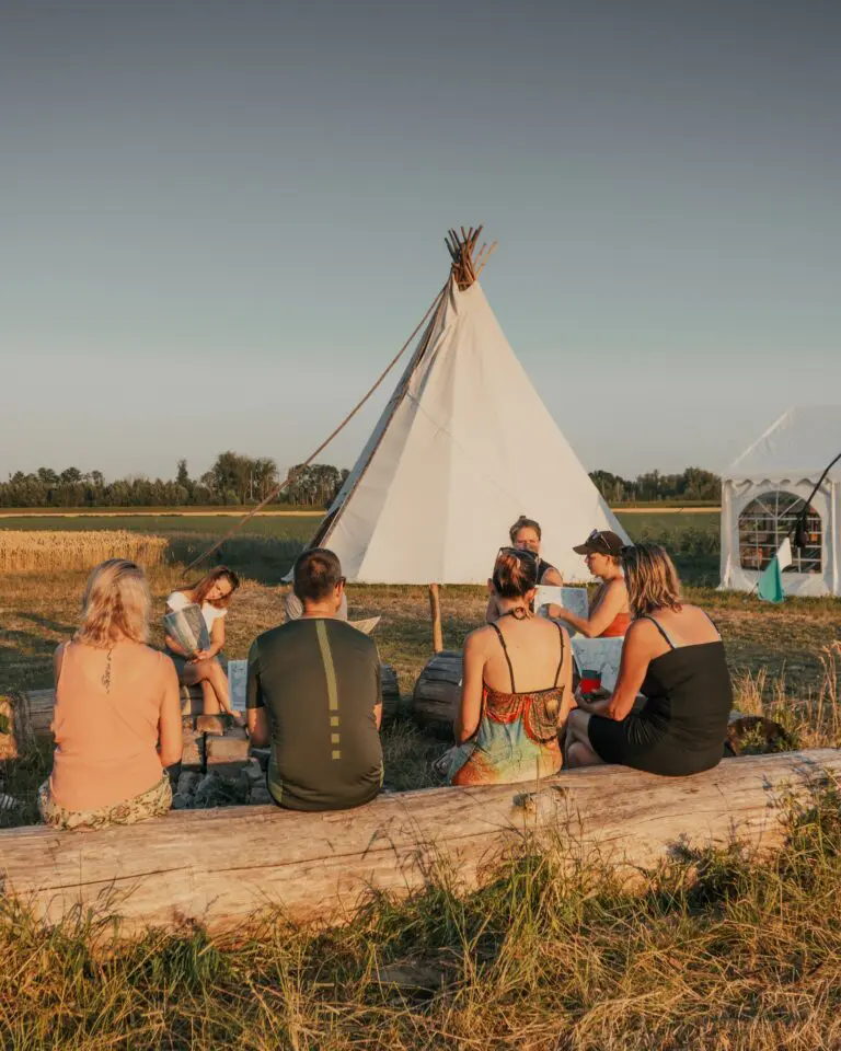 groupe d’amis se détendant autour d’un tipi au coucher du soleil