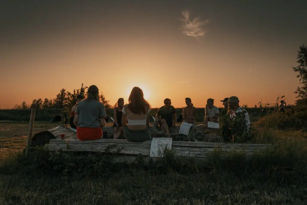 group of people sitting on a log at sunset in Biesbosch