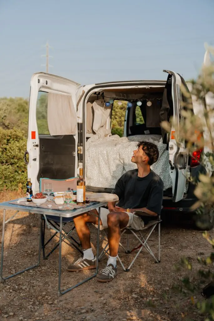young man enjoying dinner outside his campervan in Portugal