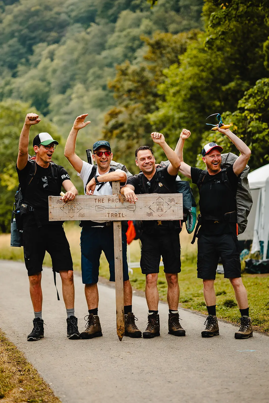 vier mannen die feestvieren bij een wandelbord op The Packraft Trail