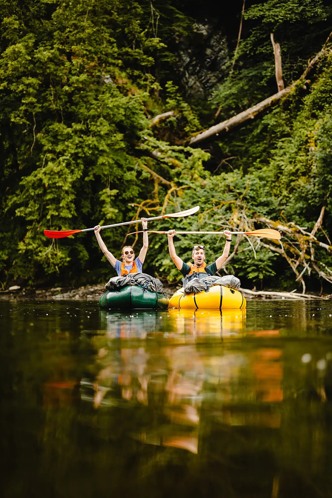 twee mensen die aan het packraften zijn op een rivier in een weelderig bos
