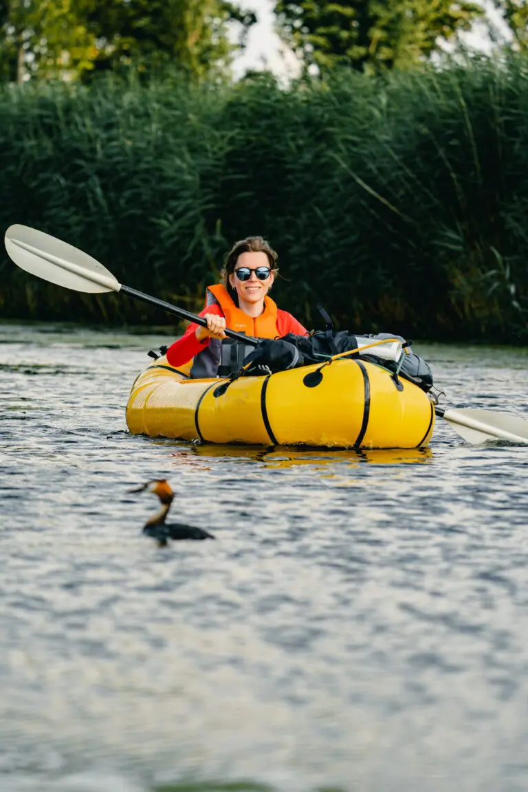 woman in yellow packraft paddling on river with duck