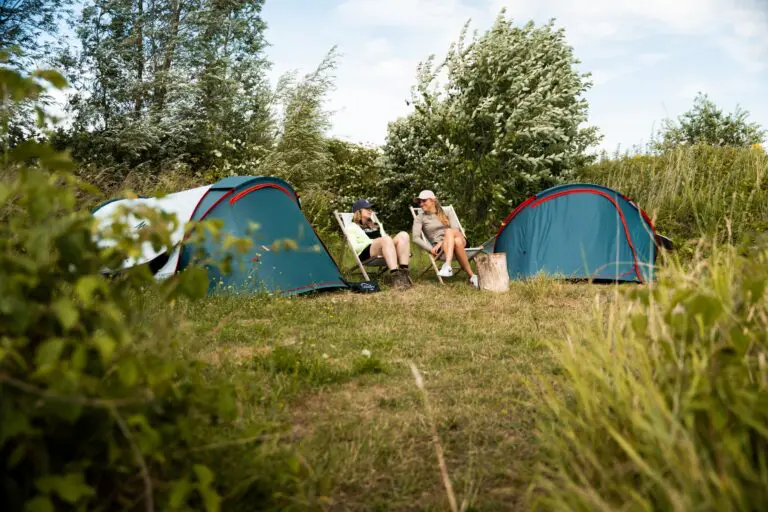 two people relaxing in camping chairs between tents in Biesbosch