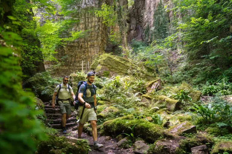 deux hommes faisant une randonnée dans un canyon verdoyant du Mullerthal
