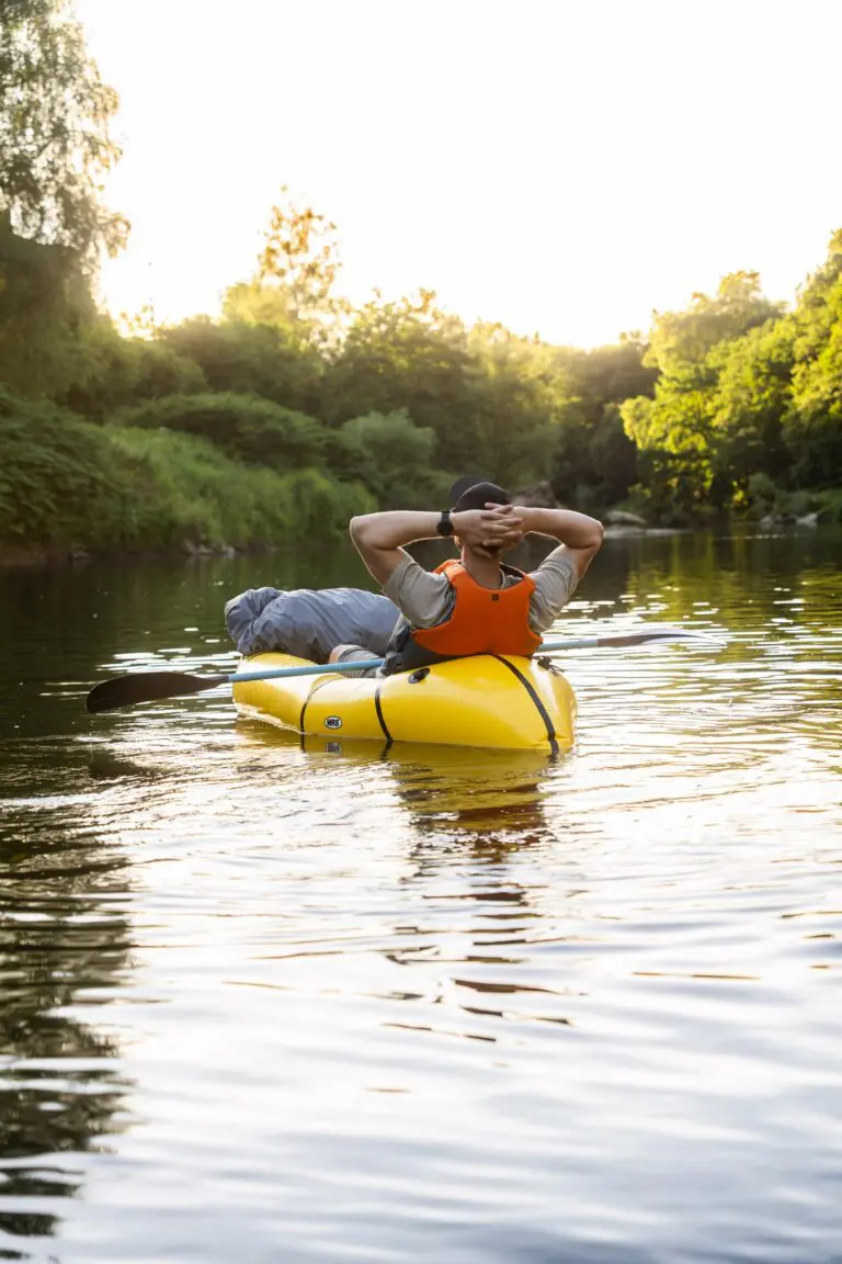 persoon die bij zonsondergang ontspant in een gele packraft op de rivier