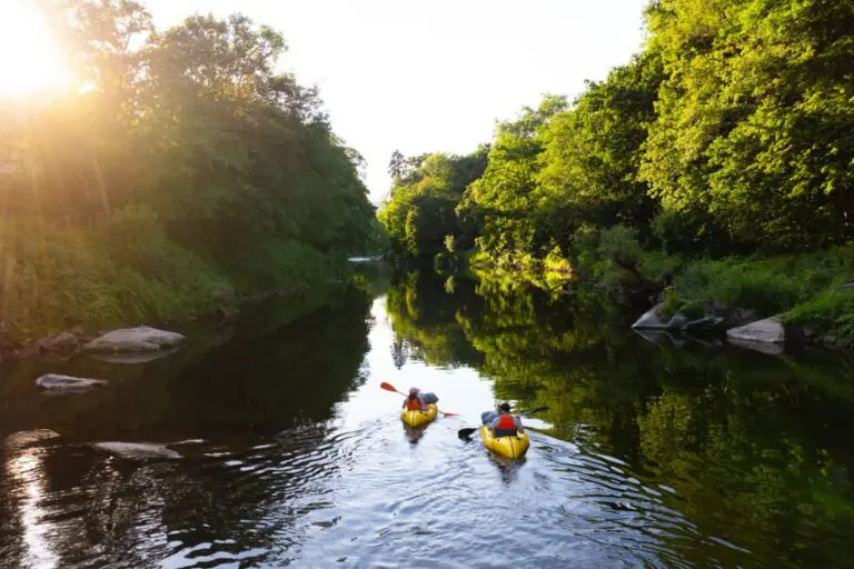 deux personnes faisant du kayak sur une rivière au coucher du soleil à Mullerthal