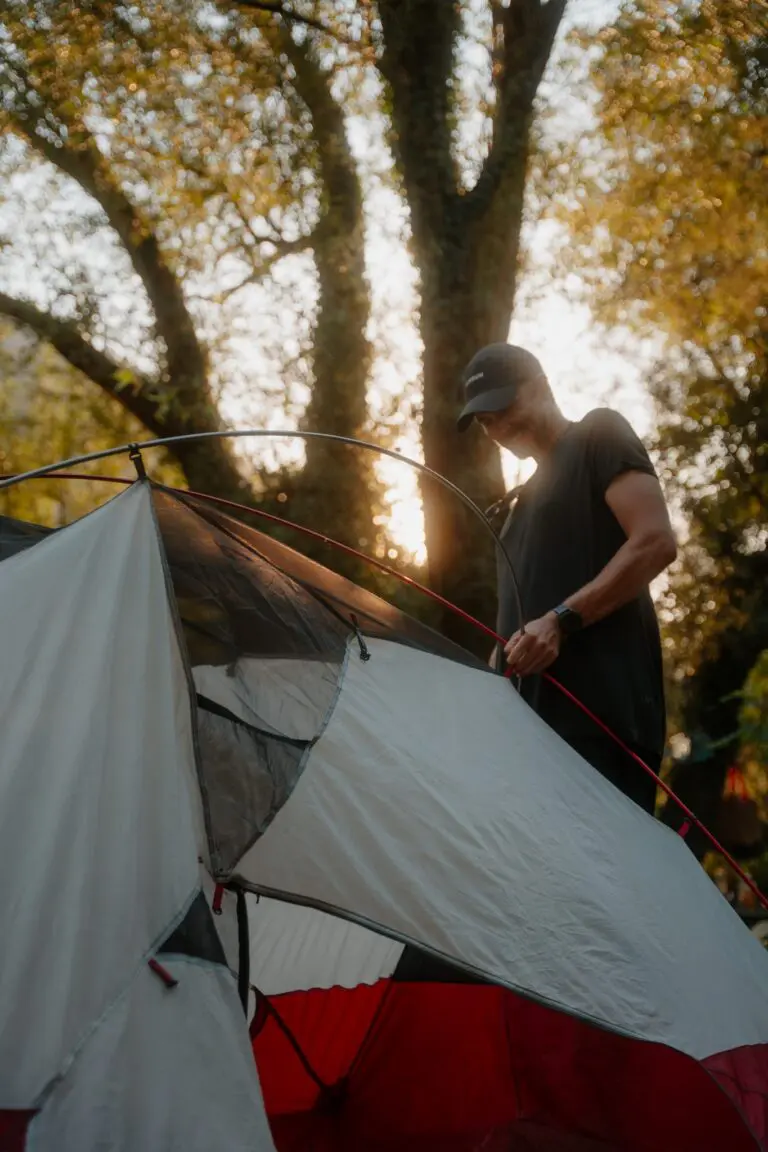 person setting up a tent in a forest at sunset