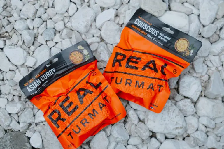 two orange Real Turmat meal pouches on white rocks