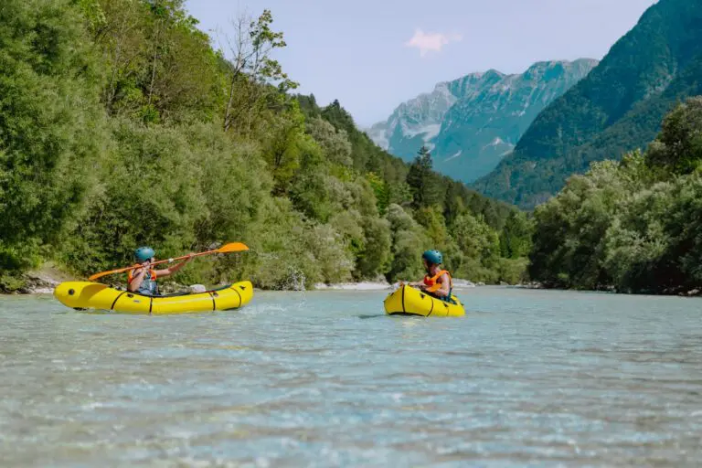 two people packrafting on a clear river in Slovenia mountains