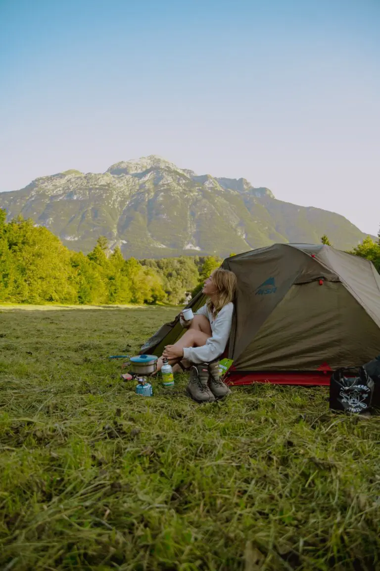 woman camping by tent with mountains in Slovenia