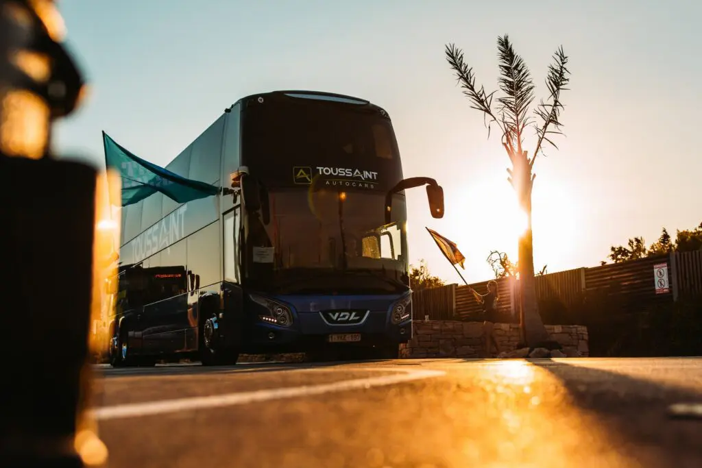 double-decker bus at sunset with a person waving a flag