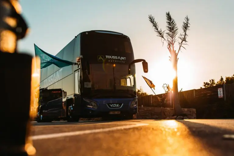 double-decker bus at sunset with a person waving a flag